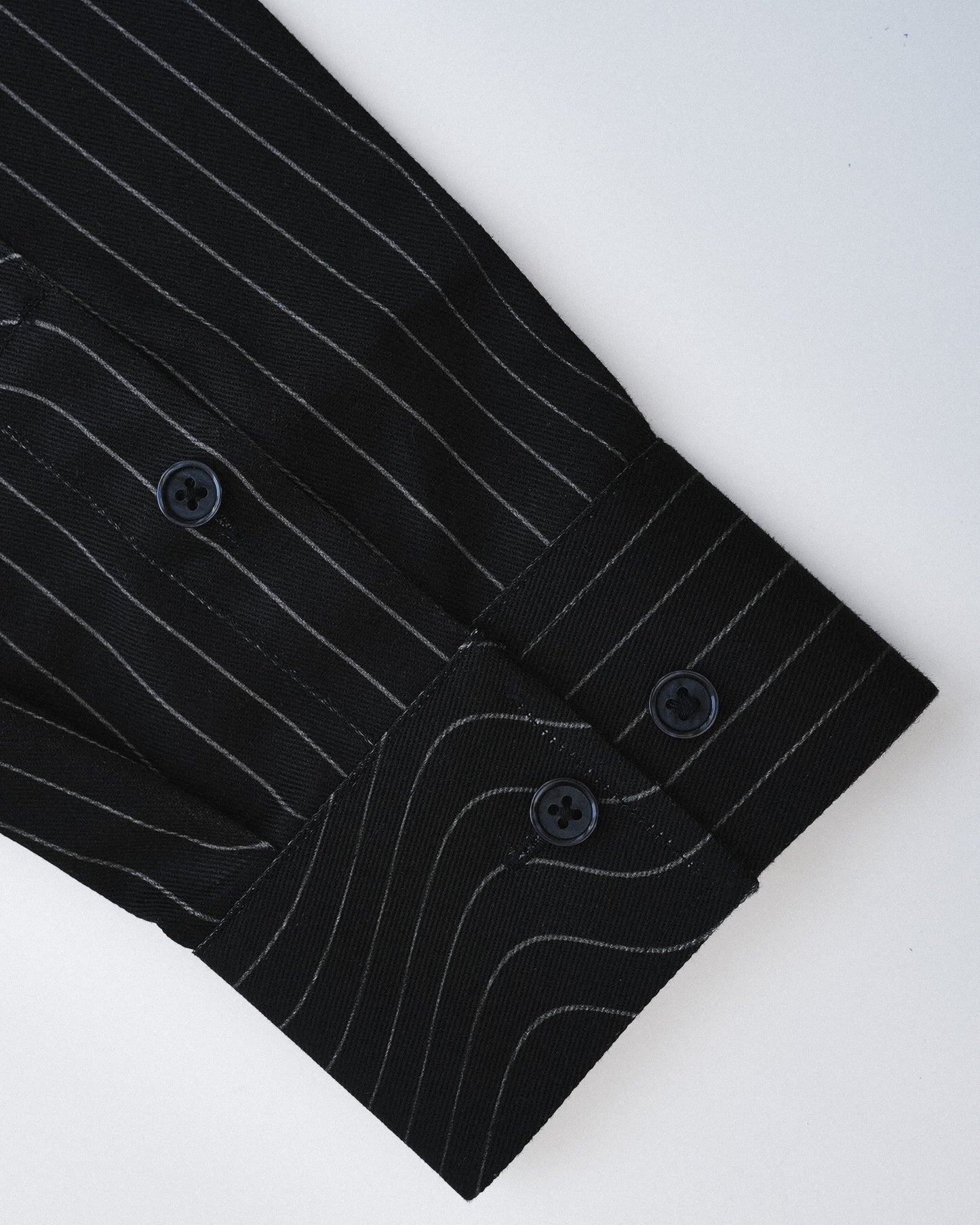 Close-up of a black pinstripe shirt with buttons on a white background