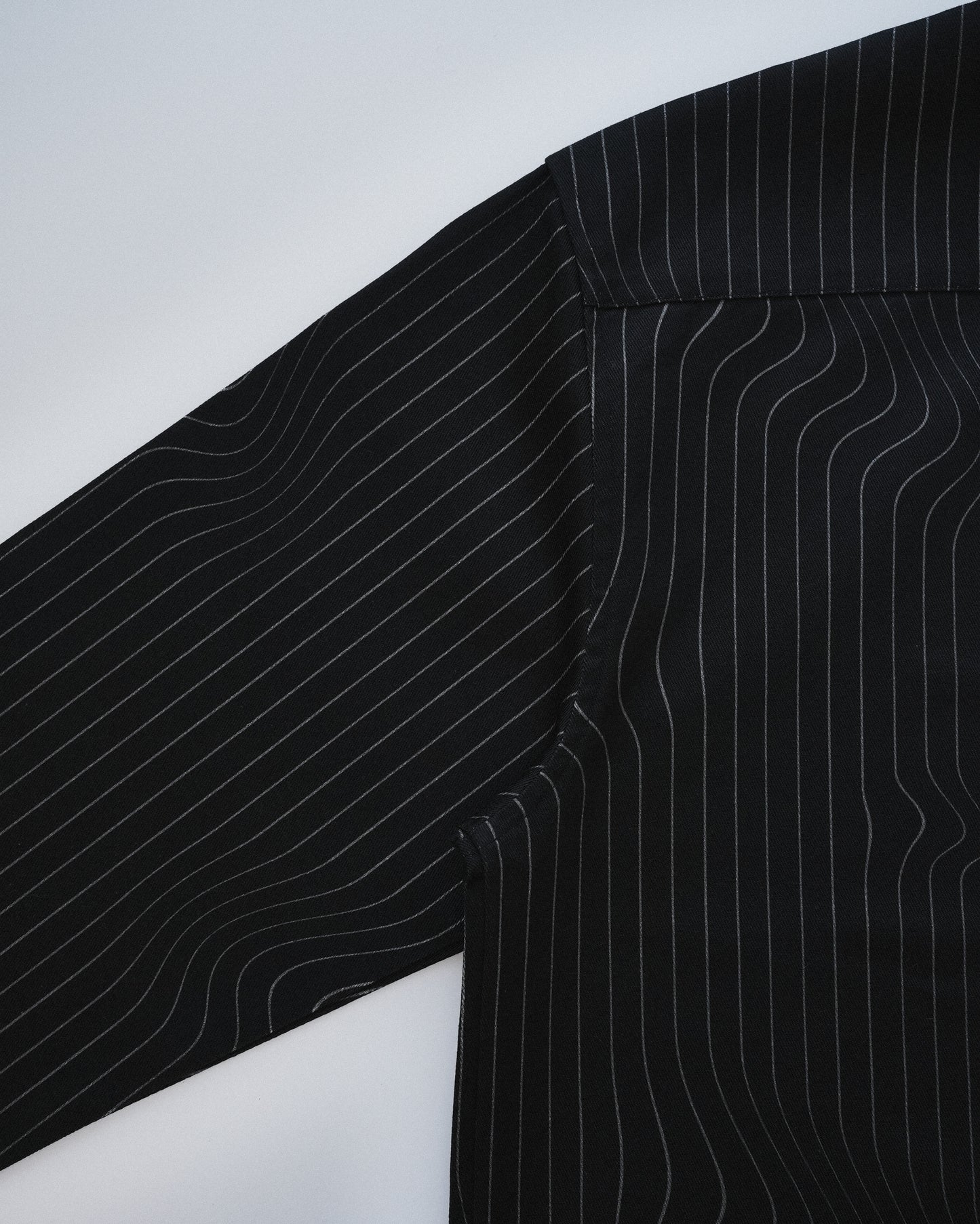 Close-up of a black pinstripe shirt on a white background