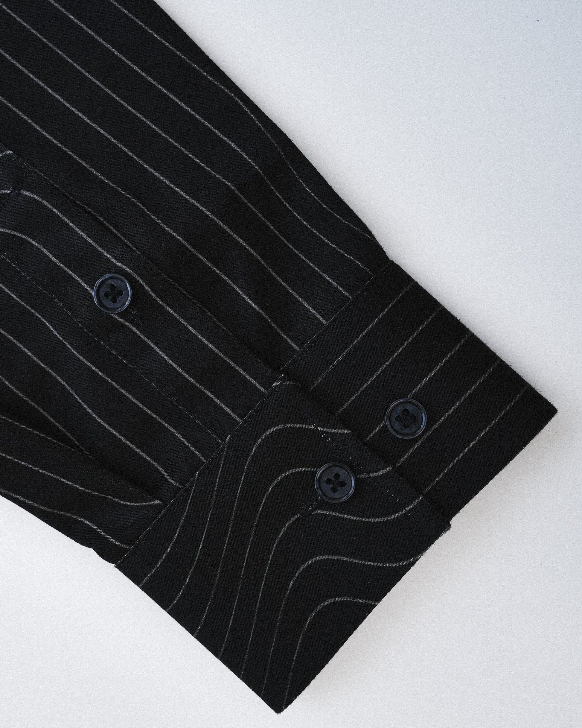 Close-up of a black pinstripe shirt with buttons on a white background