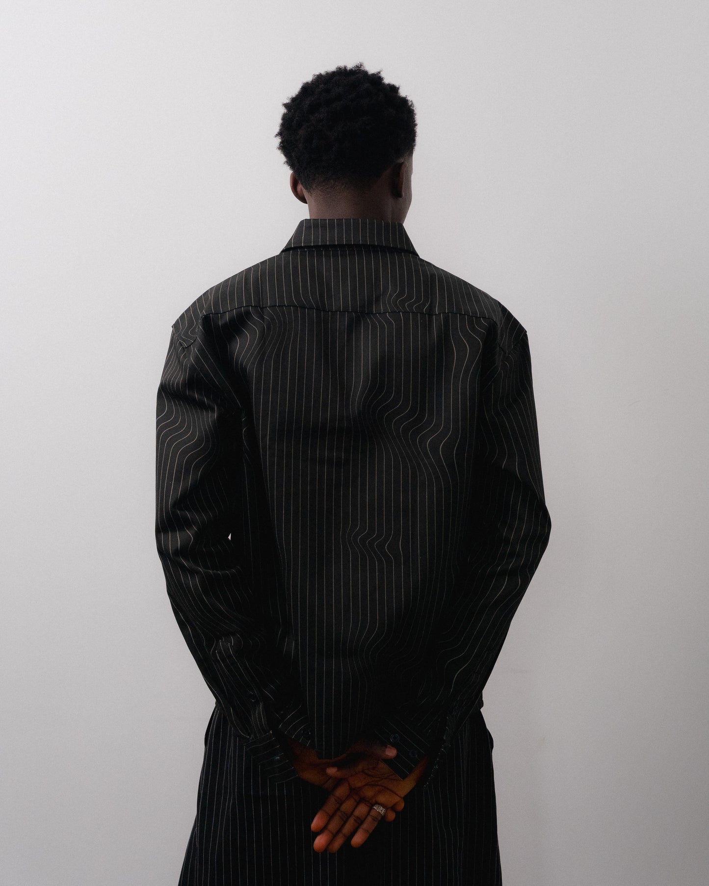 Person wearing a black pinstripe shirt against a white background