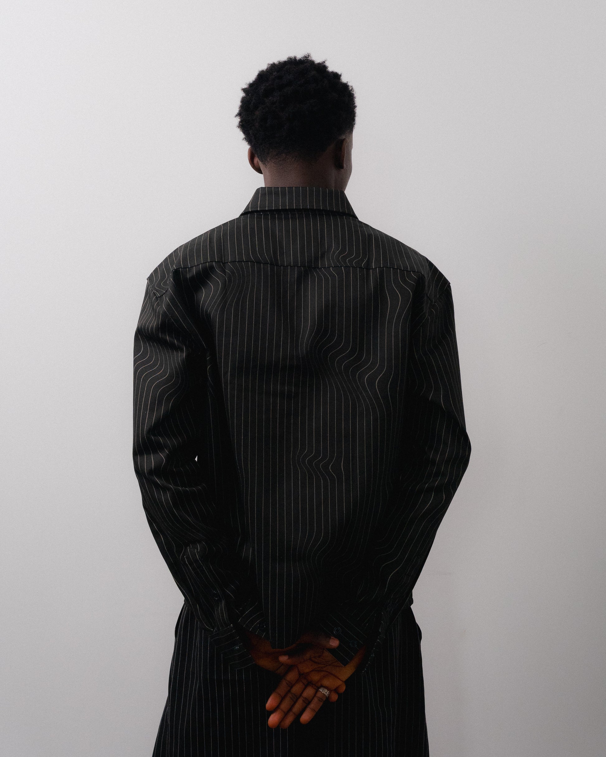 Person wearing a black pinstripe shirt against a white background