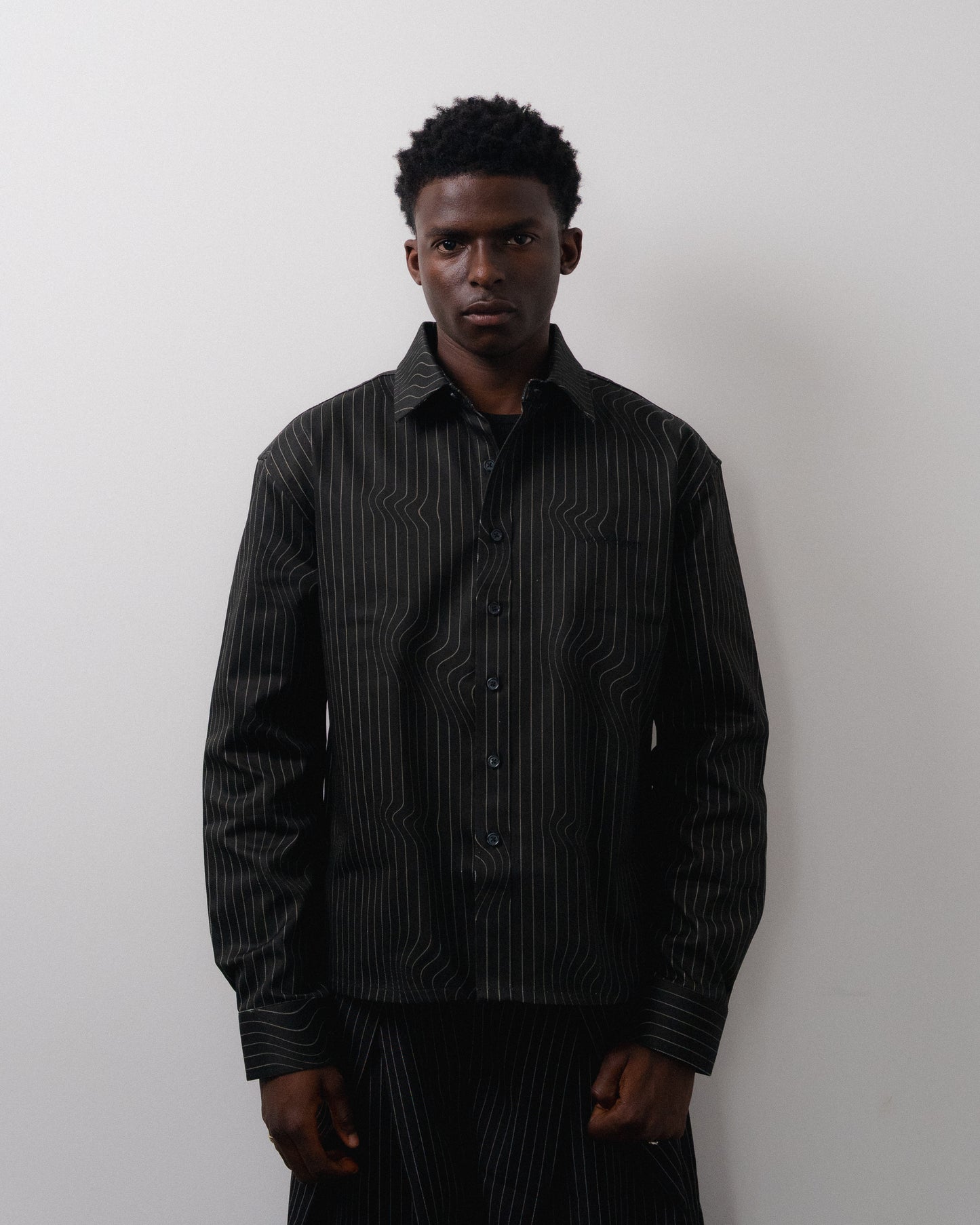 Man wearing a black pinstripe shirt against a white background